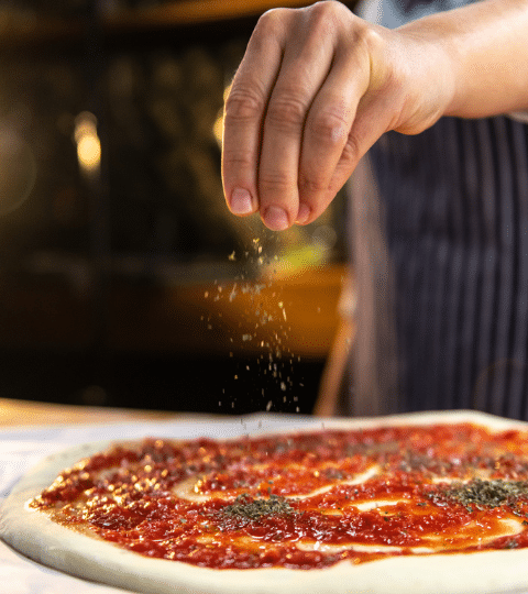 Pizza Maker sprinkling oregano